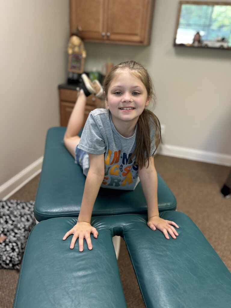 Kid on adjusting table smiling.